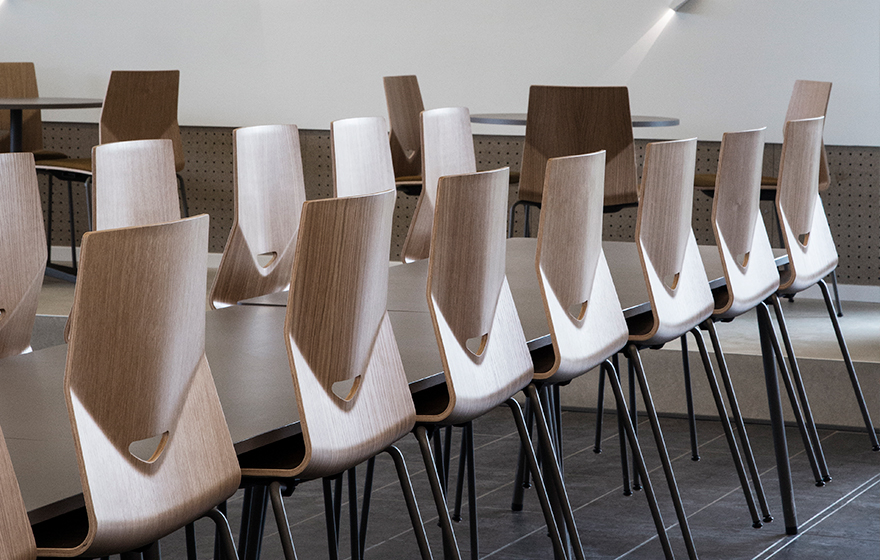 A row of wooden light weight office chairs in a conference room.
